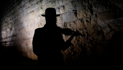 An ultra orthodox Jew playing violin in front of the Old City walls Jerusalem Israel