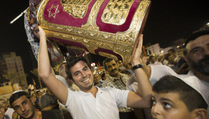 A Jewish man holds a Torah scroll during the Simhat Torah celebration in the Mediterranean coastal city of Netanya, north of Tel Aviv, on September 26, 2013. Simhat Torah is a joyous Jewish celebration that marks the end of the annual cycle of the reading of the entire Torah and the beginning of the new cycle. AFP PHOTO / JACK GUEZ (Photo credit should read JACK GUEZ/AFP via Getty Images)