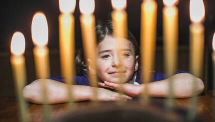 photo of a girl looking at hanukkah candles