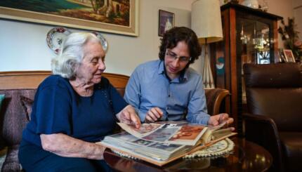 photo of an older woman and younger man looking at a photo album