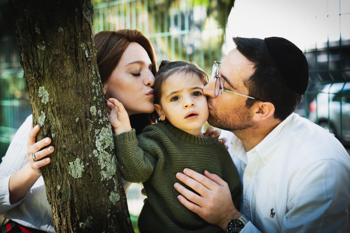 Photo of a Jewish couple kissing their child.