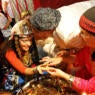A richly-adorned bride whose hand is being annointed with henna.