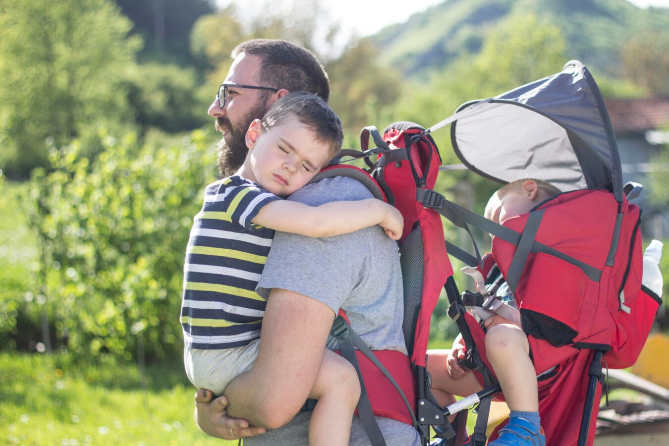 Father carrying two sleeping children.