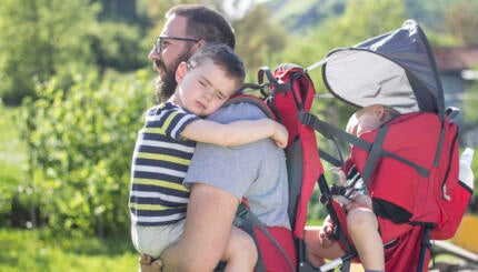 Father carrying two sleeping children.